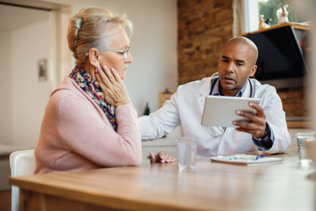 african american doctor using touchpad while talking senior woman nursing home scaled